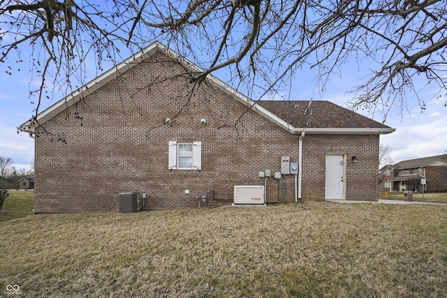 view of side of home featuring brick siding, a lawn, central AC, and roof with shingles