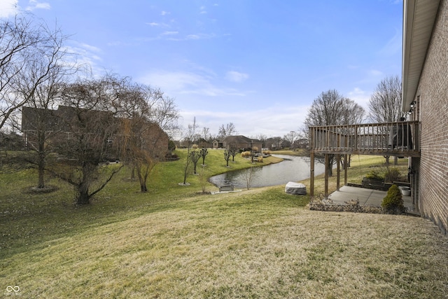 view of yard featuring a deck with water view and a patio