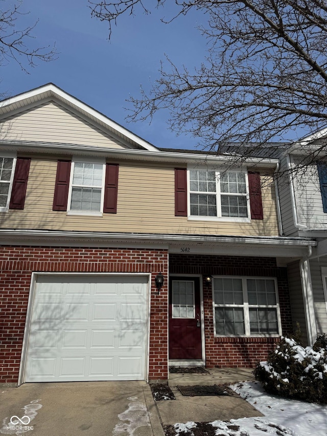 traditional home with driveway, an attached garage, and brick siding