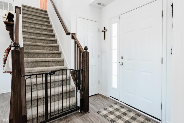 foyer with stairs, wood finished floors, visible vents, and baseboards