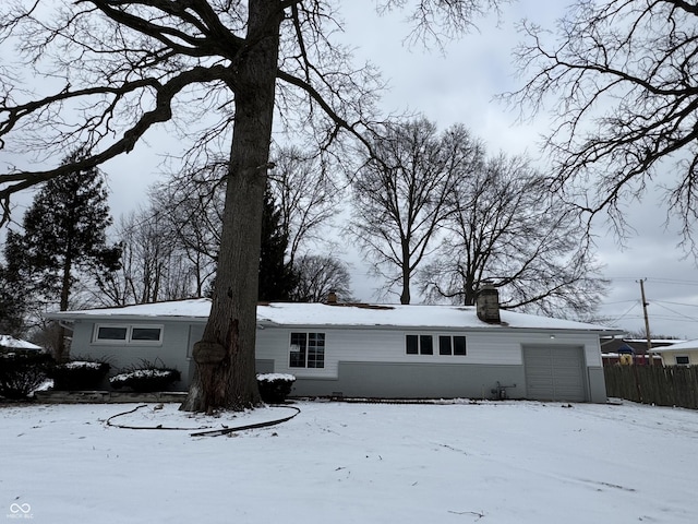 view of front of property featuring a garage, fence, and a chimney