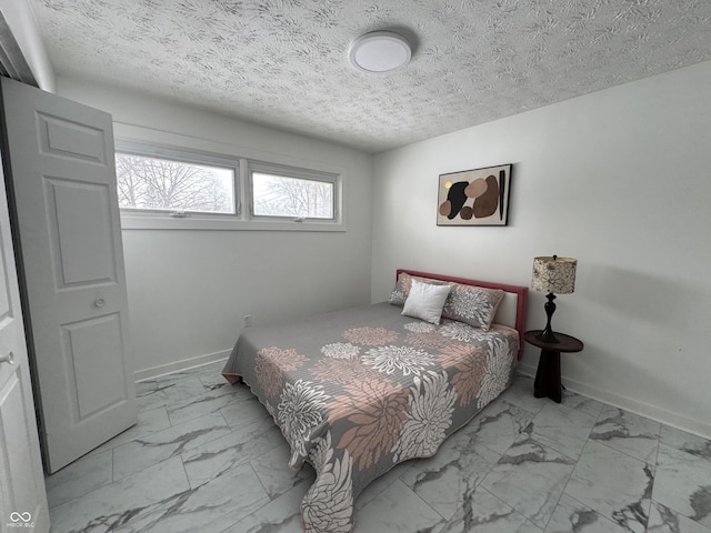 bedroom with a textured ceiling, marble finish floor, and baseboards