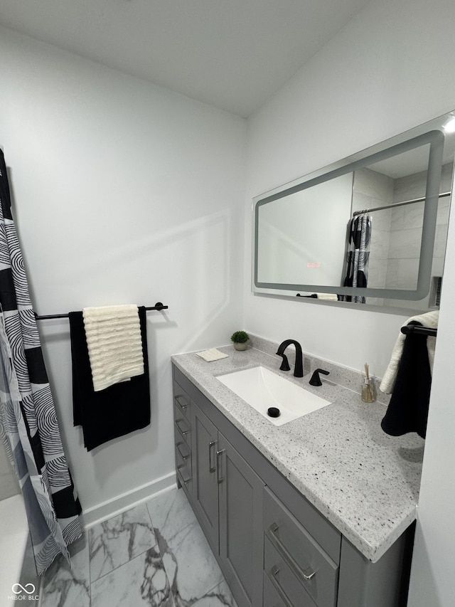 full bathroom with marble finish floor, baseboards, and vanity