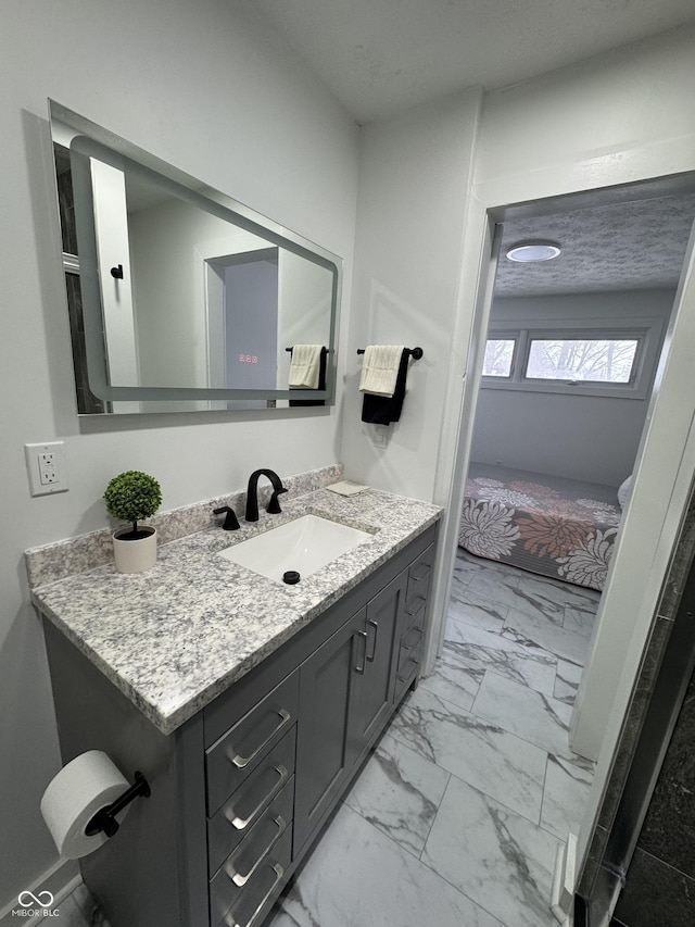 ensuite bathroom featuring marble finish floor, ensuite bath, a textured ceiling, and vanity