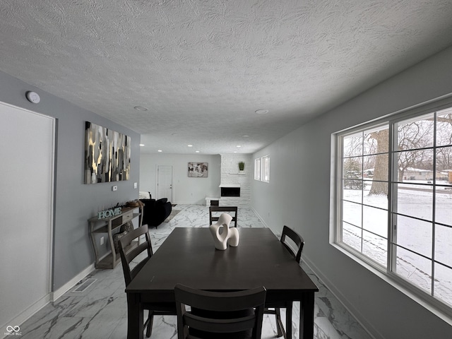 dining area featuring marble finish floor, a fireplace, and baseboards