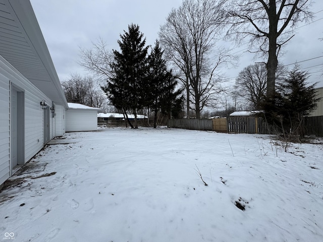 yard layered in snow with a garage and fence