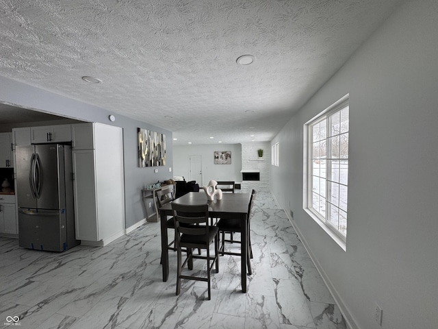 dining space with a textured ceiling, marble finish floor, and baseboards