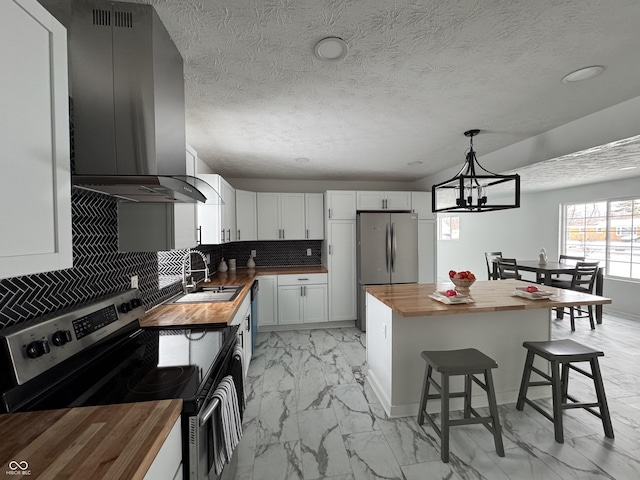 kitchen featuring stainless steel appliances, butcher block countertops, ventilation hood, and white cabinetry