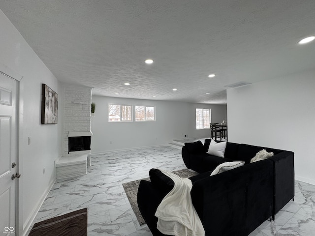 living area featuring a textured ceiling, recessed lighting, a large fireplace, baseboards, and marble finish floor