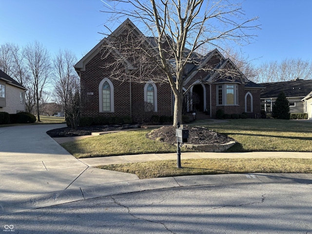 view of front facade with brick siding and a front yard