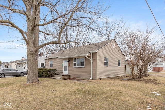 view of front facade with a shingled roof and a front yard