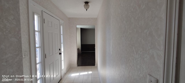 entryway with a textured wall and light tile patterned flooring