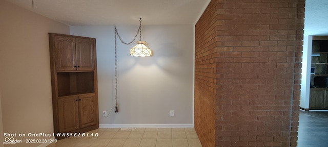 unfurnished dining area with brick wall and baseboards