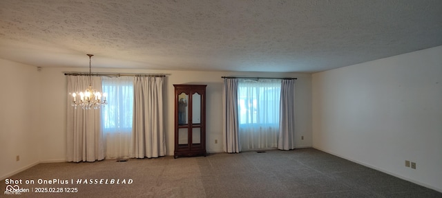 unfurnished room featuring a chandelier, a textured ceiling, carpet, and baseboards