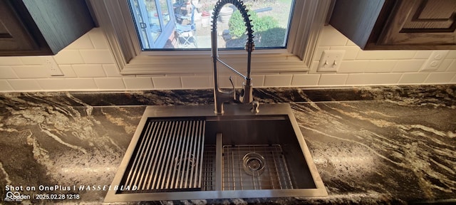 interior details with dark countertops, backsplash, and a sink