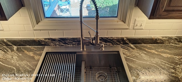 interior details with dark stone counters, a sink, and decorative backsplash