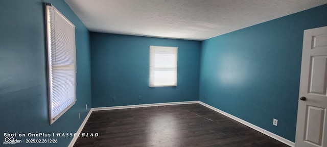 empty room with a textured ceiling, baseboards, and wood finished floors