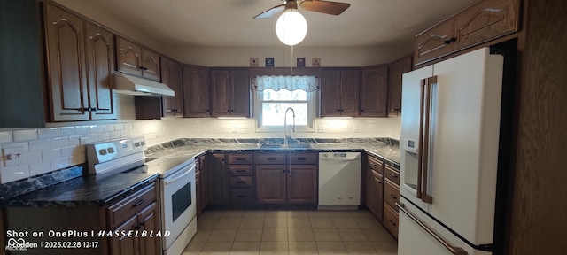 kitchen with light tile patterned flooring, under cabinet range hood, white appliances, a sink, and decorative backsplash