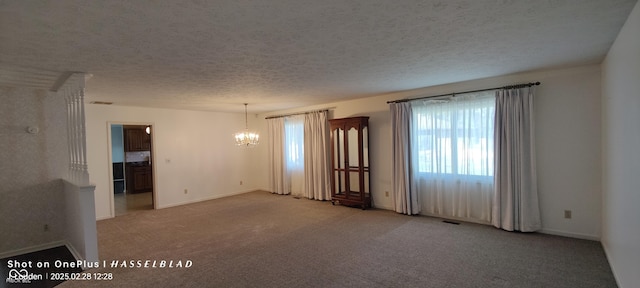 carpeted spare room featuring a chandelier, visible vents, and a textured ceiling