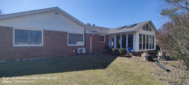 rear view of property featuring a sunroom, a lawn, ac unit, and brick siding