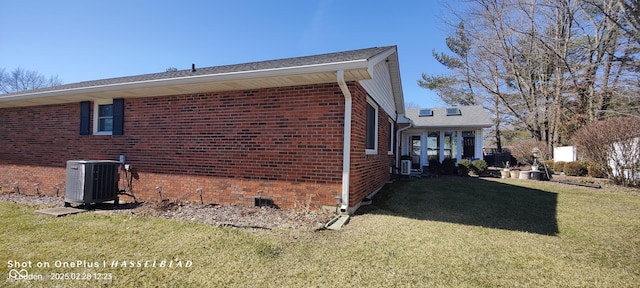 view of side of home with a yard, cooling unit, and brick siding