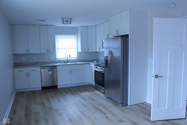 kitchen featuring light wood-style flooring, a sink, visible vents, white cabinets, and appliances with stainless steel finishes