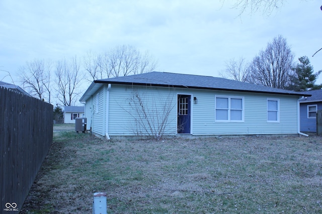 back of house with a yard, a shingled roof, cooling unit, and fence