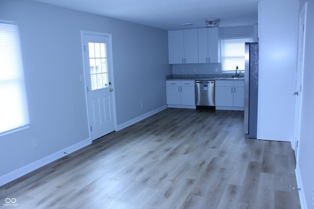 kitchen featuring stainless steel appliances, light wood-type flooring, plenty of natural light, and white cabinetry