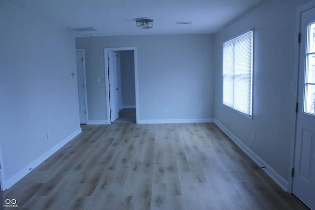 empty room with visible vents, baseboards, and wood finished floors