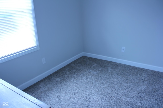 empty room featuring dark carpet and baseboards