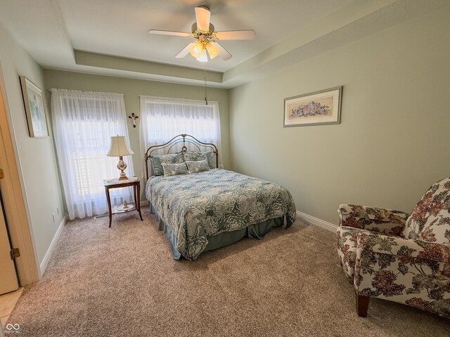 bedroom featuring ceiling fan, baseboards, a raised ceiling, and carpet flooring