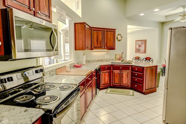 kitchen with light tile patterned floors, stainless steel appliances, a sink, a ceiling fan, and reddish brown cabinets