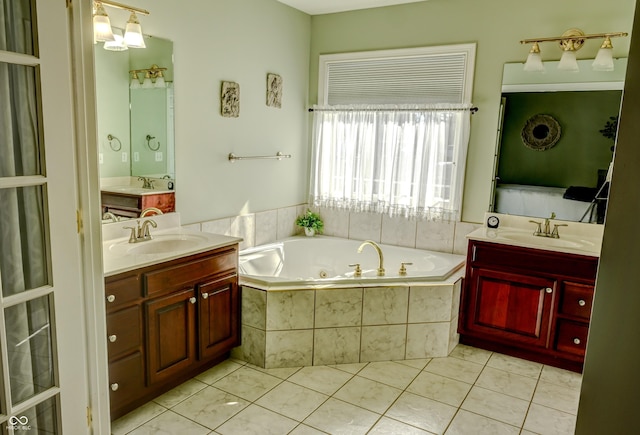 bathroom with a tub with jets, two vanities, tile patterned flooring, and a sink