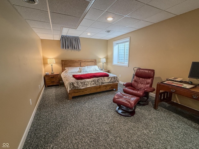 bedroom with a drop ceiling, dark carpet, and baseboards