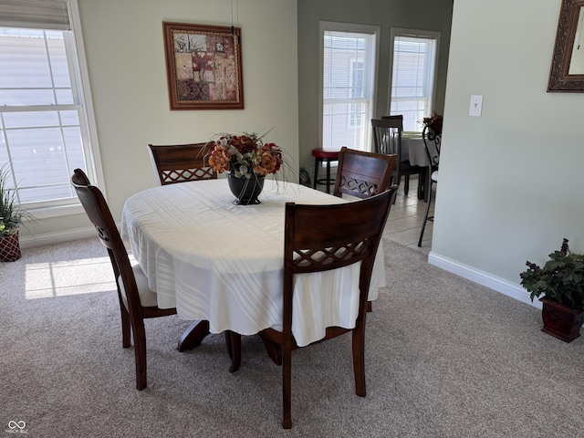 dining space with baseboards and light colored carpet