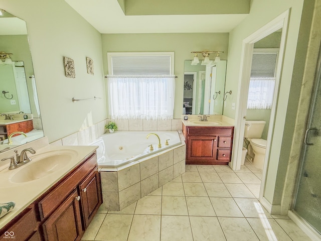 bathroom with a jetted tub, two vanities, a sink, and toilet