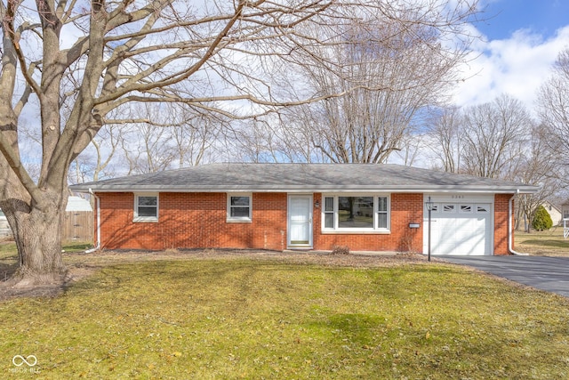 single story home featuring aphalt driveway, brick siding, roof with shingles, an attached garage, and a front lawn