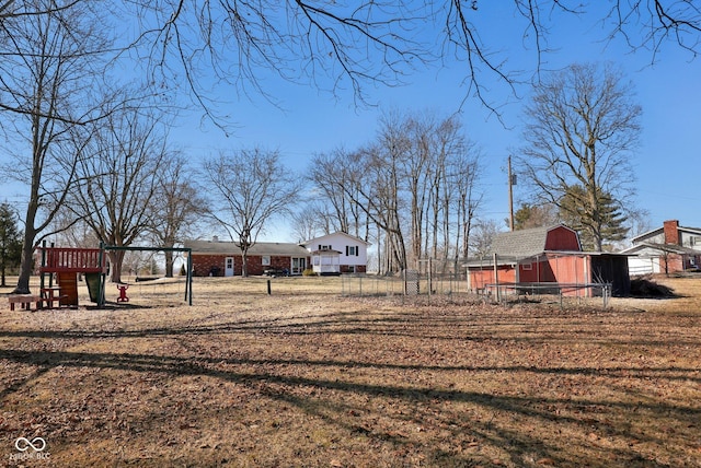 view of yard with playground community, an outbuilding, a barn, and fence