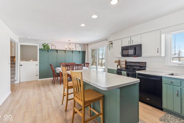 kitchen featuring black appliances, light wood-style flooring, white cabinets, and light countertops