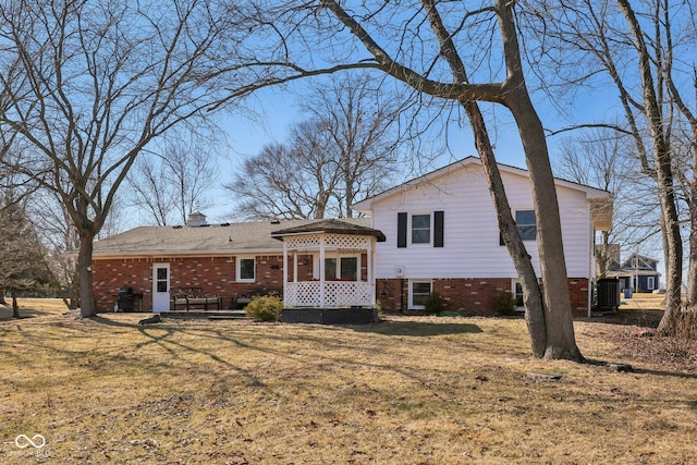 back of house featuring a yard and brick siding