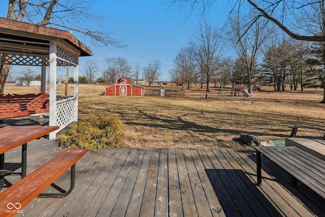 deck featuring a lawn, an outdoor structure, a shed, and a playground