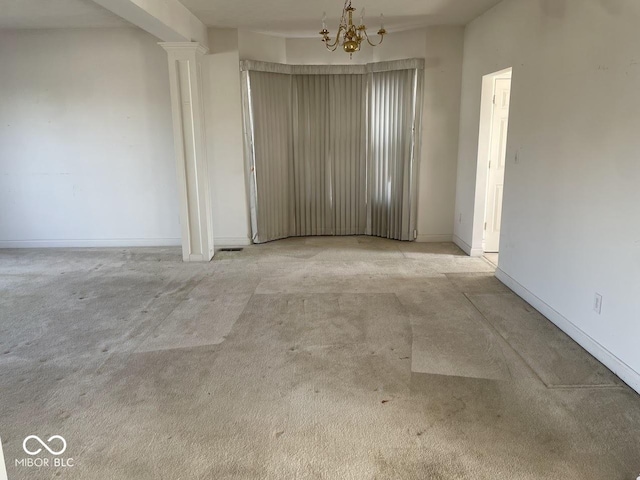 spare room with a chandelier, light colored carpet, and baseboards