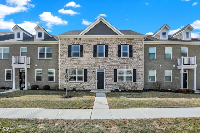 multi unit property with a front lawn and brick siding