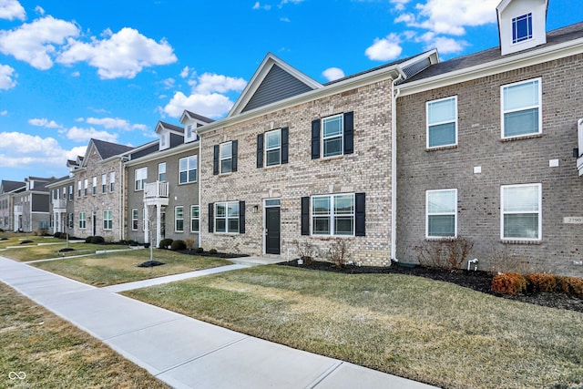 townhome / multi-family property featuring brick siding, a front yard, and a residential view