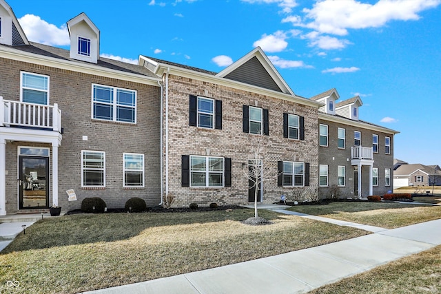 townhome / multi-family property featuring a front yard and brick siding