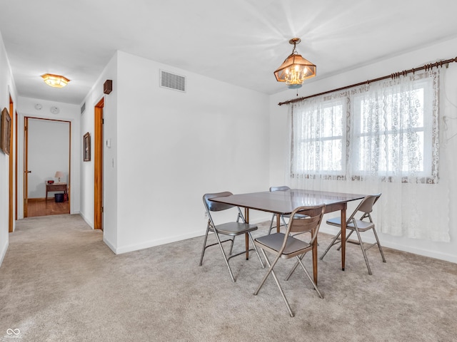 carpeted dining area featuring visible vents, a notable chandelier, and baseboards