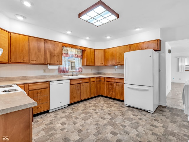 kitchen featuring light countertops, backsplash, brown cabinetry, a sink, and white appliances