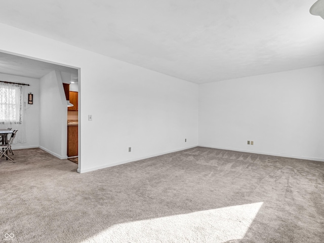 unfurnished living room with carpet and baseboards