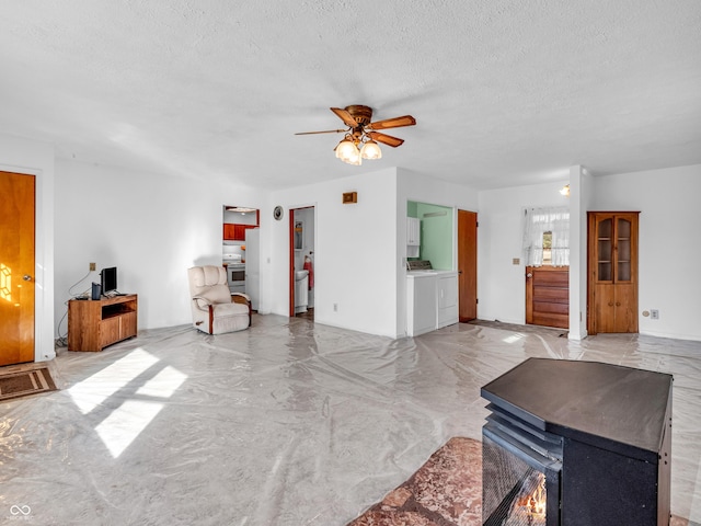 living room featuring a ceiling fan, washer / clothes dryer, and a textured ceiling