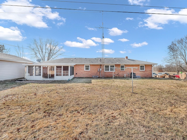 rear view of house featuring a sunroom, brick siding, and a yard